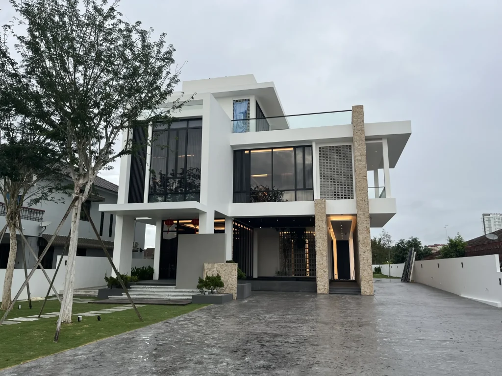 Contemporary three-level residence completed by Madoc in Muar, Johor, with interior lighting visible through the glazing
